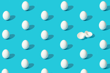 White eggs pattern (broken and whole) on a blue background viewed from above.  Copy space