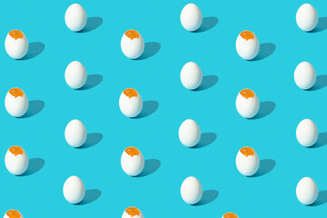 White eggs pattern (broken and whole) on a blue background viewed from above. Top view. Copy space