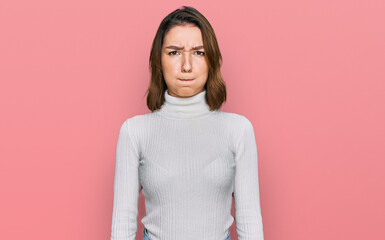 Young caucasian girl wearing casual clothes puffing cheeks with funny face. mouth inflated with...