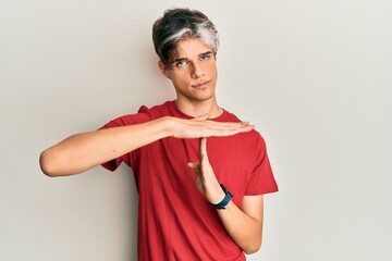 Young hispanic man wearing casual clothes doing time out gesture with hands, frustrated and serious...