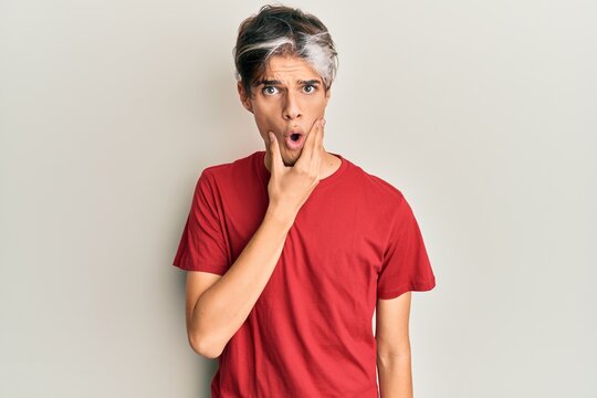 Young hispanic man wearing casual clothes looking fascinated with disbelief, surprise and amazed expression with hands on chin