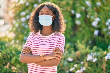 Young african american girl wearing medical mask standing at the park.