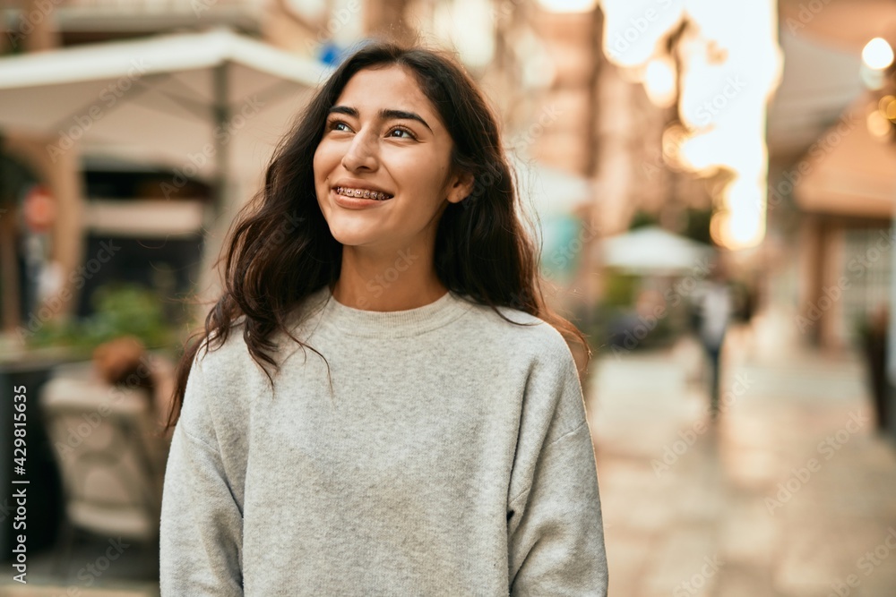 Wall mural Young middle east girl smiling happy standing at the city.