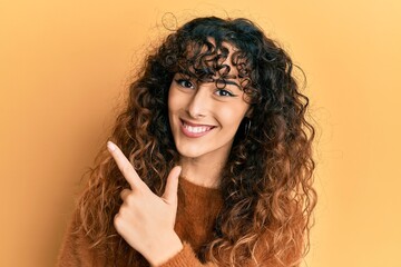 Young hispanic girl wearing casual clothes smiling cheerful pointing with hand and finger up to the side