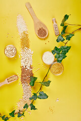 Flat lay of set heap various grains and cereals bulgur, rice, oatmeal, buckwheat, couscous wheat seeds, greens leaves on grey background, copy space, space for text, top view. Eco, organic, natural