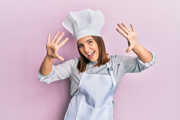 Young beautiful woman wearing professional cook uniform and hat showing and pointing up with fingers number ten while smiling confident and happy.