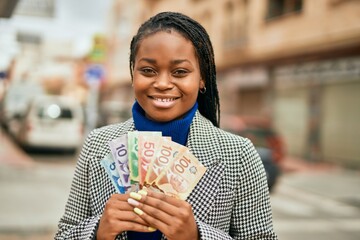 Young african american businesswoman smiling happy holding canadian dollars at the city.