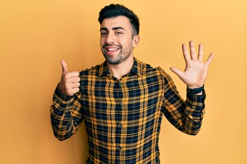 Young hispanic man wearing casual clothes showing and pointing up with fingers number six while smiling confident and happy.