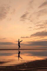 silhouette of a man at sunset, man on the beach doing yoga or training, physical and breathing practices in nature. skein beach at sunset, tall and slender man standing on his hands and in warrior
