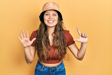 Young hispanic girl wearing casual clothes and hat showing and pointing up with fingers number...