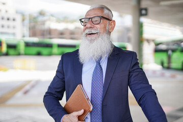 Hipster business senior man holding digtial tablet at bus station