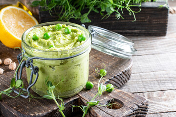 Glass jar of green hummus, delicious cream of chickpeas and green pea. Vegetarian snack. Copy space