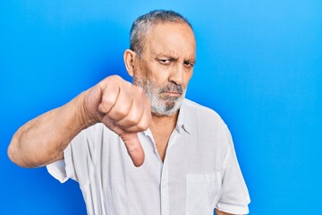 Handsome senior man with beard wearing casual white shirt looking unhappy and angry showing rejection and negative with thumbs down gesture. bad expression.