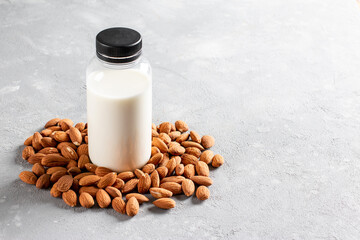 Almond milk in bottle with almonds on light background. Substitute for dairy milk. Copy space
