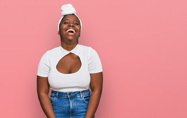 Young african woman with turban wearing hair turban over isolated background smiling and laughing hard out loud because funny crazy joke with hands on body.