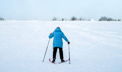 A woman in a blue jacket skiing up a snowy slope.