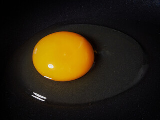 Egg on a black background. Broken chicken egg. The yolk spilled onto the table