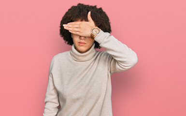 Young hispanic girl wearing wool winter sweater covering eyes with hand, looking serious and sad....
