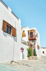 Fototapeta na wymiar Narrow street with houses whitewashed walls and wooden shutters on windows