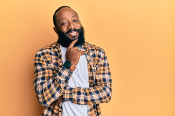 Young african american man wearing casual clothes smiling looking confident at the camera with crossed arms and hand on chin. thinking positive.