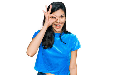 Fototapeta premium Young hispanic woman wearing casual clothes doing ok gesture with hand smiling, eye looking through fingers with happy face.