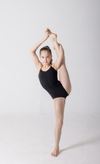 preteen girl gymnast trains on white background in black leotard. children's professional sports....