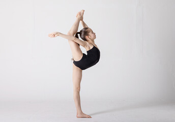 preteen girl gymnast trains on white background in black leotard. children's professional sports. rhythmic gymnastics.