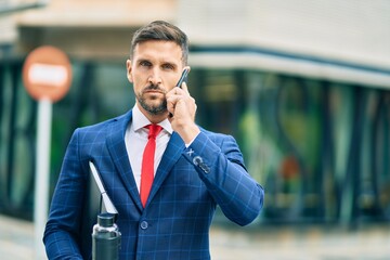 Young caucasian businessman with serious expression talking on the smartphone at the city.