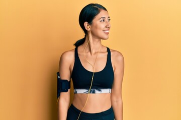 Obraz premium Beautiful asian young sport woman wearing sportswear and earphones looking away to side with smile on face, natural expression. laughing confident.