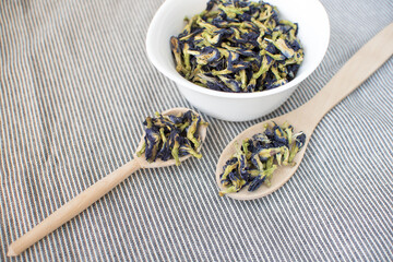 Dry flowers of blue anchan tea lie on a colored cloth towel, on a wooden background spoon and dask  