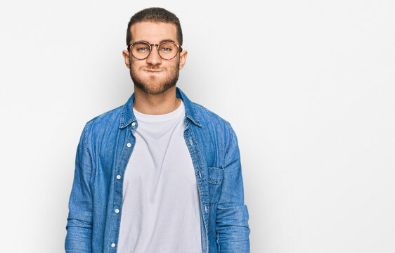 Young caucasian man wearing casual clothes puffing cheeks with funny face. mouth inflated with air, crazy expression.