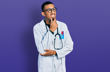 Young african american man wearing doctor uniform and stethoscope thinking worried about a question, concerned and nervous with hand on chin