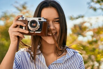 Young hispanic tourist girl smiling happy using camera at the park