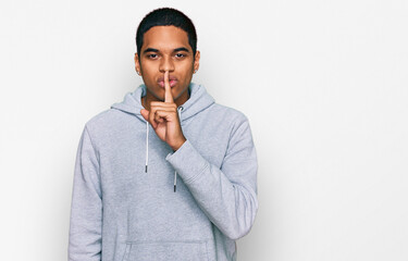 Young handsome hispanic man wearing casual sweatshirt asking to be quiet with finger on lips....