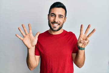 Naklejka premium Young hispanic man wearing casual clothes showing and pointing up with fingers number eight while smiling confident and happy.