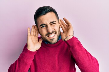 Young hispanic man wearing casual clothes trying to hear both hands on ear gesture, curious for gossip. hearing problem, deaf