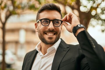 Young hispanic businessman smiling happy standing at the city.