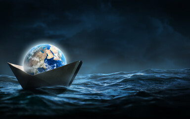 Planet earth in a paper boat floating in the ocean. Faith or religion conceptual theme.