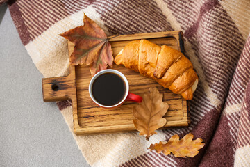 Board with cup of coffee and croissant on grey background