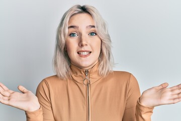 Young blonde girl wearing casual clothes clueless and confused expression with arms and hands...
