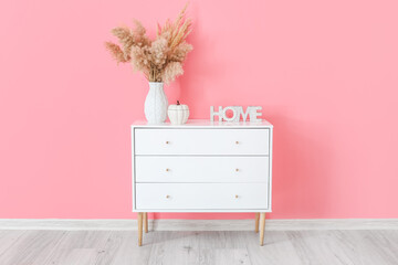 Chest of drawers with floral decor near color wall