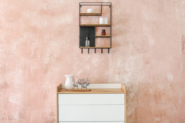 Stylish chest of drawers with decor near color wall