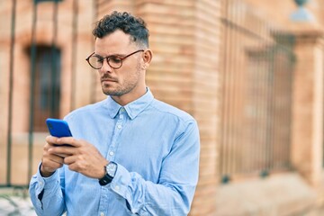 Young hispanic businessman with serious expression using smartphone at the city.