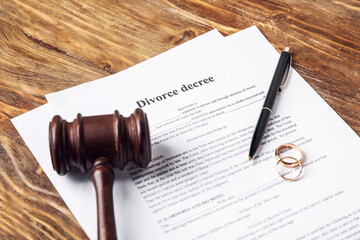 Divorce decree with judge's gavel and rings on wooden background