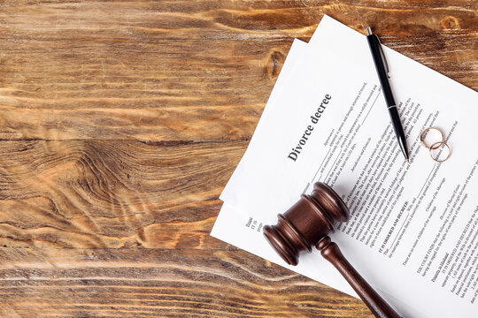 Divorce decree with judge's gavel and rings on wooden background