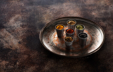 Various Indian spices, spicy and.  seasoning in metal containers on a dark background