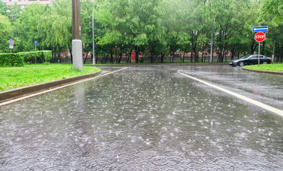 Heavy rain with hail in the city on a summer day. Large puddles on the roadway. Wet road with puddles of spray.
