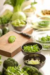 Bowls with fresh vegetables on light background