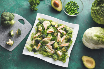 Plate of tasty salad with fresh vegetables and chicken on color background