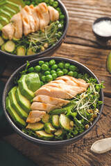 Bowls of tasty salad with fresh vegetables and chicken on wooden background